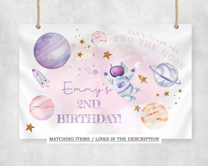 May include: A pink and white birthday banner with the text "let's blast off TWO THE MOON" and "Emmy's 2ND BIRTHDAY!"  The banner features an astronaut, planets, stars, and a rocket.