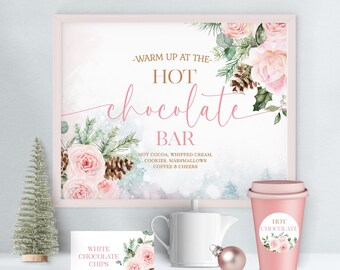 Può includere: Un cartello rosa e bianco con un design floreale recita "Warm up at the Hot Chocolate Bar". Il cartello è accanto a una tazza rosa e bianca con un adesivo floreale che recita "Hot Chocolate". C'è anche un creamer in ceramica bianca e un piccolo ornamento rosa.