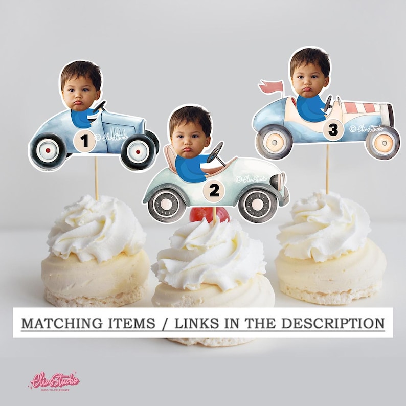 Op de afbeelding: Cupcake toppers met een babygezicht in lichtblauwe oldtimer raceauto's. De auto's hebben zwarte wielen en de nummers 1, 2 en 3. De cupcakes zijn bedekt met witte glazuur. De tekst onderaan luidt "MATCHING ITEMS / LINKS IN THE DESCRIPTION."