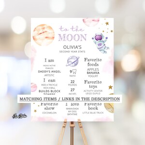 May include: A pink and purple illustrated poster with a space theme. The poster features a cartoon astronaut, planets, and stars. The text on the poster reads "To the Moon, Olivia's Second Year Stats". The poster also includes information about Olivia's age, height, weight, and favorite foods and toys.