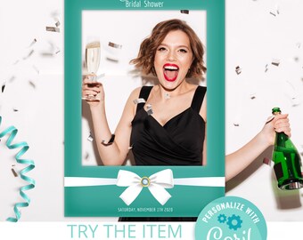 Op de afbeelding: Een turquoise fotoboothframe met de tekst "Chloe's Bridal Shower" en "Saturday, November 1th 2020". Het frame heeft een witte strik met een gouden middenstuk. Een vrouw staat in het frame en houdt een champagneglas en een fles champagne vast.