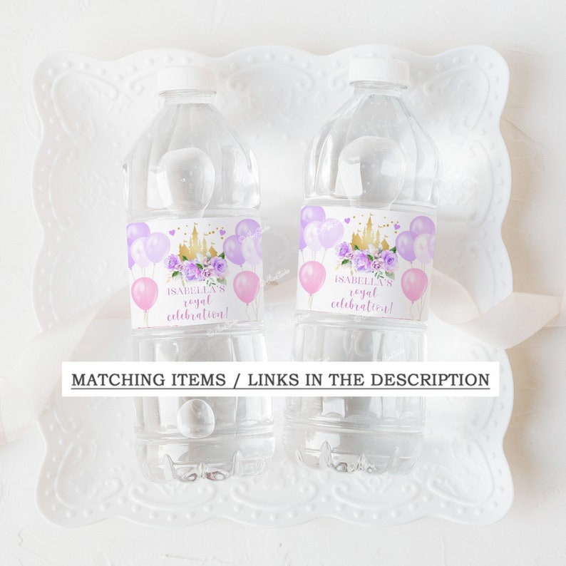 Op de afbeelding: Twee doorzichtige plastic waterflessen met paarse en roze etiketten. De etiketten tonen een gouden kasteel, paarse bloemen en roze ballonnen. De tekst op de etiketten luidt "Isabella's royal celebration!"