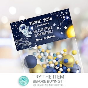 May include: A blue and white thank you favor bag with a space-themed design. The bag features an astronaut, a UFO, stars, and the text "Thank You! It was a blast! Have a safe trip back to your home planet! Oliver's 5th Birthday."
