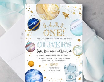 May include: A blue and gold space-themed first birthday party invitation with a cartoon astronaut, planets, and stars. The invitation reads "5,4,3,2... ONE! Please join us as we celebrate Oliver's first trip around the sun. Sunday, November 14th, 2:00 PM. The Boulevard, 350 West Dillon Road Colorado Springs. RSVP to my mum by 11/12/20XX."