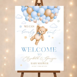 Può includere: Un cartello di benvenuto per baby shower su un cavalletto. Il cartello presenta un orsacchiotto che tiene dei palloncini, con il testo "We can bearly wait" e "Welcome to Elizabeth & Georges Baby Shower Sunday February 12th". Il design include colori blu e oro.
