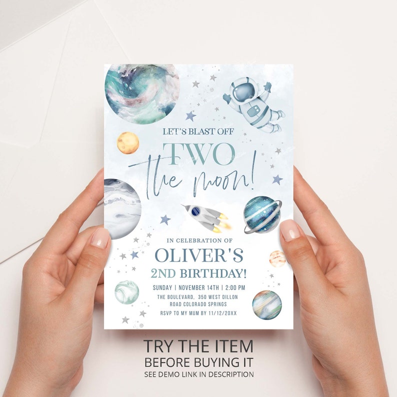 May include: A blue and white invitation card with a watercolor illustration of planets, stars, and an astronaut. The text on the card reads "Let's Blast Off Two The Moon!" and "Oliver's 2nd Birthday!"