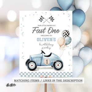 Op de afbeelding: Een lichtblauw raceauto-verjaardagsfeestbord met de tekst "Our Little Racer is a Fast One - Welcome to Oliver's birthday party". Het bord heeft een geblokt vlagontwerp en is versierd met ballonnen.