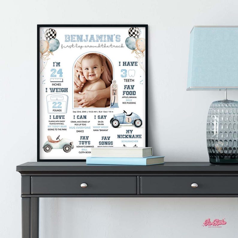 Op de afbeelding: Een ingelijste baby-mijlpaalafdruk met een foto van een baby. De afdruk bevat de naam van de baby, afmetingen (61 cm, 10 kg), favoriete dingen en andere details. Decoratieve ballonnen en raceautographics zijn inbegrepen.