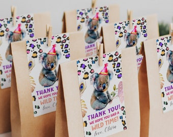 May include: Thank you favor bags with a watercolor koala wearing a party hat. The bags have a leopard print and peacock feather design. The text on the bags reads "Thank you! We hope you had a wild time! love. Olivia."