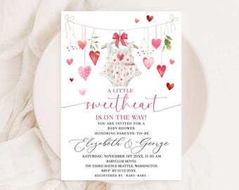 May include: A pink and white baby shower invitation featuring a watercolour illustration of a baby onesie hanging from a string of hearts. The text reads "A Little Sweetheart is on the Way!" and includes the names "Elizabeth & George" and details for the baby shower.