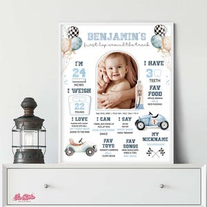 Op de afbeelding: Een ingelijste baby-mijlpaalposter met een foto van een baby. De poster bevat de naam van de baby, de afmetingen, favoriete dingen en mijlpalen. De poster heeft een racewagenthema met blauwe en witte accenten.