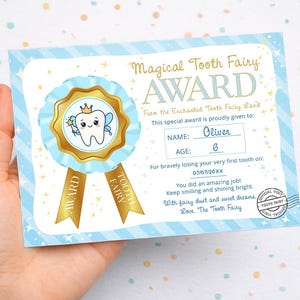 May include: A blue and white "Magical Tooth Fairy Award" certificate. The certificate features a cartoon tooth with a crown and wings, and gold ribbons that say "Award" and "Tooth Fairy". The certificate is personalized with the name "Oliver" and age "6".