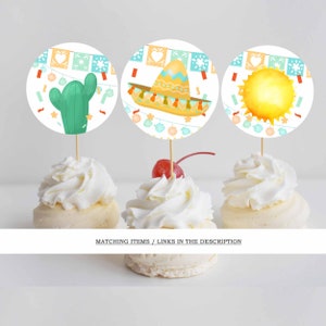 May include: Three cupcakes topped with decorative toppers. The toppers feature a green cactus, a sombrero, and a sun. The toppers are round with a festive design. The cupcakes are decorated with white frosting and a cherry.