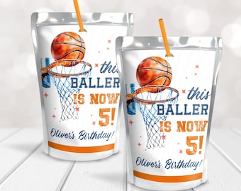 May include: Two white juice pouches with orange straws. The pouches have a basketball design with the text "this baller is now 5!" and "Oliver's Birthday!"