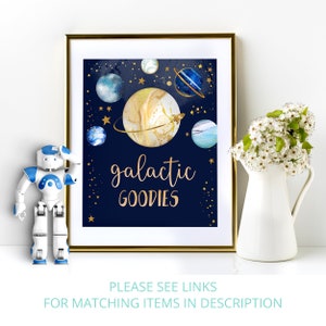 May include: A printable sign with a navy blue background and gold lettering that says "galactic goodies". The sign features a watercolor illustration of planets and stars.