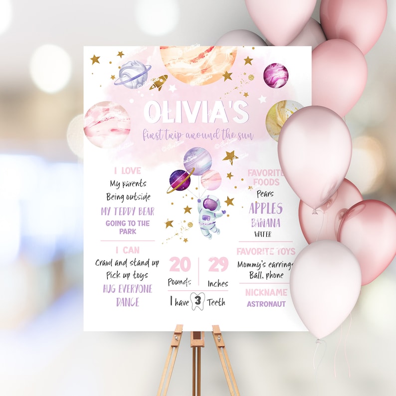 May include: A pink and purple space-themed first birthday milestone poster with the name Olivia. The poster features a cartoon astronaut holding balloons shaped like planets. The poster lists the child's age, weight, height, favorite foods, toys, and other milestones.