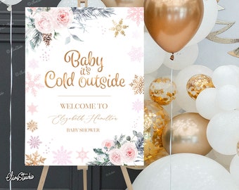 May include: A white and pink baby shower welcome sign with gold lettering that reads "Baby it's Cold Outside". The sign also includes the text "Welcome to Elizabeth Hamilton Baby Shower" and features a floral design with snowflakes.