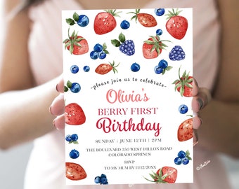 May include: A white invitation card with a berry theme. The card features a watercolor illustration of strawberries, blueberries, and blackberries. The text on the card reads "Olivia's Berry First Birthday" and includes the date, time, and location of the party. RSVP information is also included.