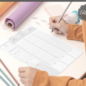 May include: A weekly planner with a calendar, a notes section, and a to-do list. The planner is printed on white paper with gray lines and is laid out on a white surface.