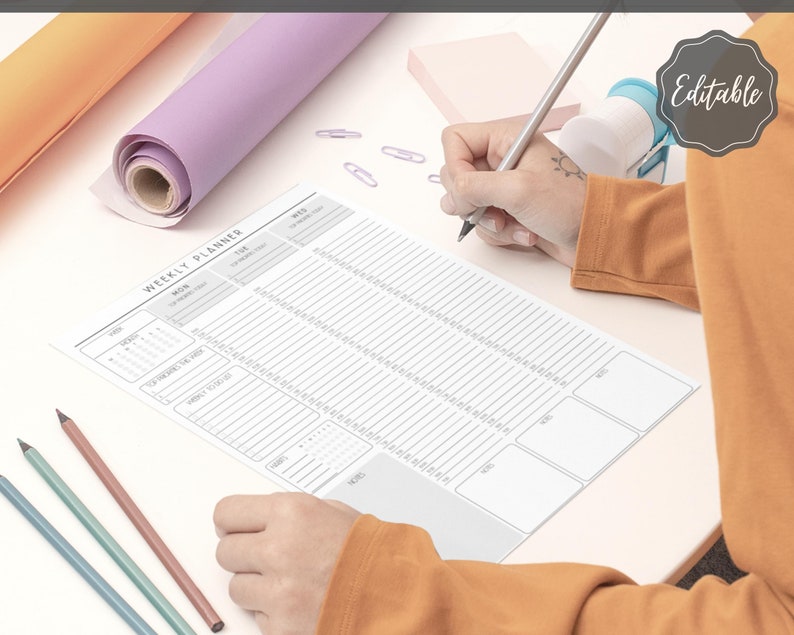 May include: A weekly planner with a calendar, a notes section, and a to-do list. The planner is printed on white paper with gray lines and is laid out on a white surface.