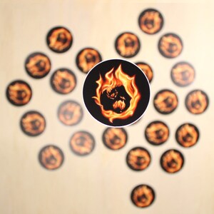 Puede incluir: Una colección de pegatinas redondas con un diseño naranja y amarillo llameante sobre un fondo negro. Las pegatinas presentan una imagen estilizada de un globo envuelto en llamas.