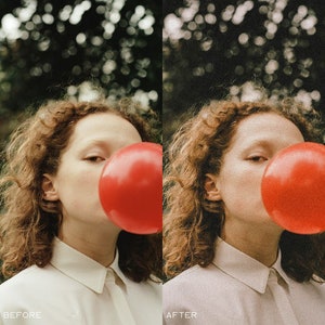 May include: A woman with curly red hair is blowing a large red bubble. She is wearing a white button-down shirt.
