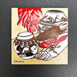 May include: A ceramic tile with a Southwestern design featuring two pottery vessels, a bunch of red chili peppers, and a corn cob. The tile is signed "L. Kuhne".