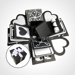 May include: Black and white explosion box with a small black gift box inside. The box has a heart, a flower, and a polka dot design.