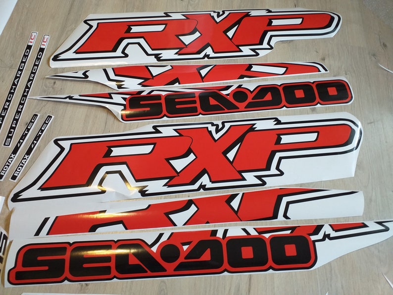 May include: A set of red and black vinyl decals for a Sea-Doo RXP watercraft. The decals feature the words "Sea-Doo" and "RXP" in a bold, stylized font.