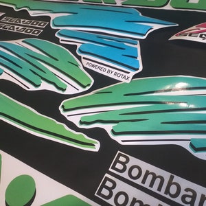 Puede incluir: Un conjunto de calcoman&iacute;as verdes, azules y blancas con el texto "Sea-Doo" y "Powered by Rotax". Las calcoman&iacute;as est&aacute;n dise&ntilde;adas para una embarcaci&oacute;n.