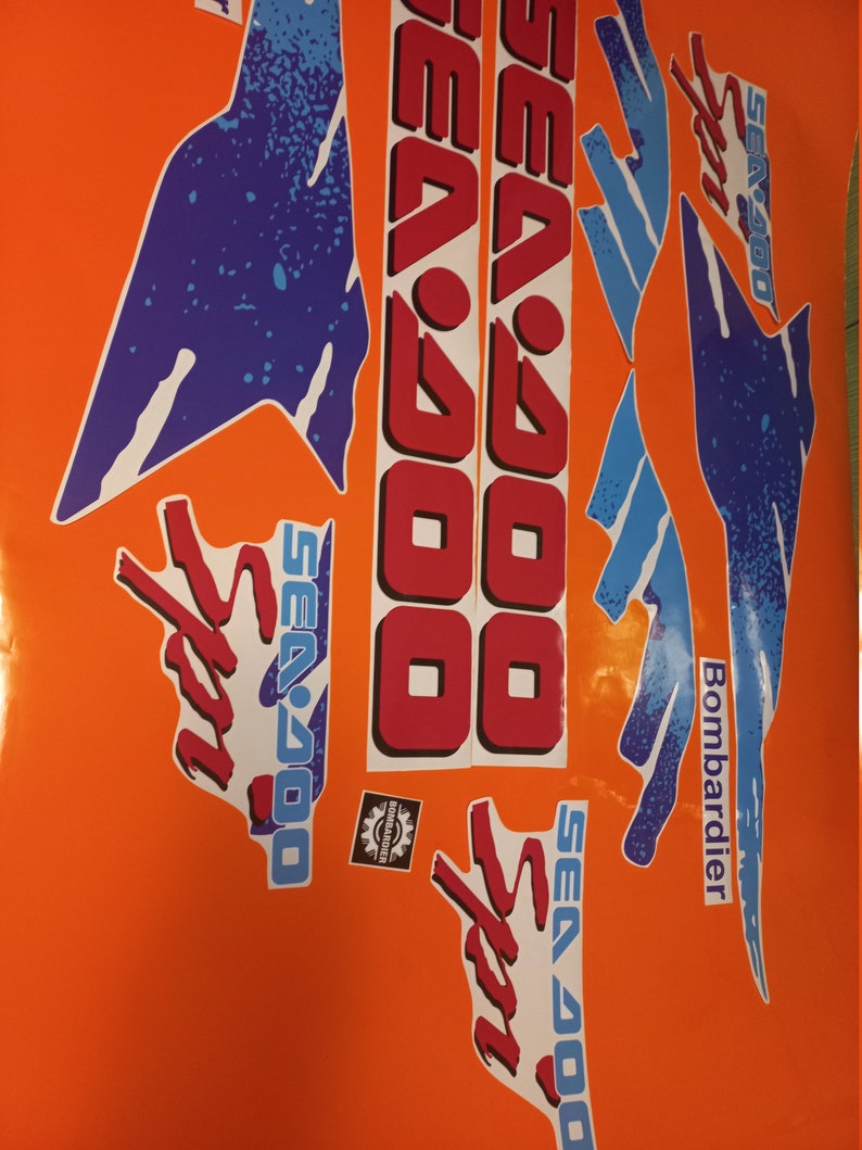 K&ouml;nnte beinhalten: Ein Satz Sea-Doo Sport-Aufkleber in Blau, Rot und Wei&szlig;. Die Aufkleber zeigen das Sea-Doo-Logo und die Worte "Sea-Doo Sport" und "Bombardier".