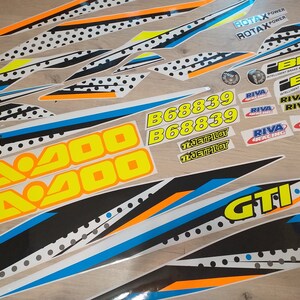 May include: A set of black, white, yellow, blue and orange decals with the text "Sea-Doo", "Sea-Doo", "B68839", "B68839", "JET PILOT", "JET PILOT", "ROTAX POWER", "ROTAX POWER", "RIVA RACING", "RIVA RACING", "RIVA RACING", "RIVA RACING", "RIVA RACING", "RIVA RACING", "GTI", and "GTI".