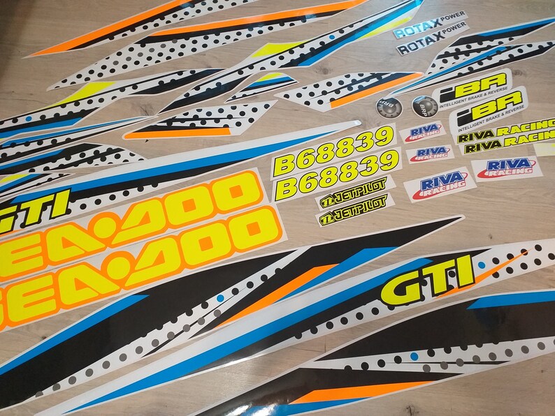 May include: A set of black, white, yellow, blue and orange decals with the text "Sea-Doo", "Sea-Doo", "B68839", "B68839", "JET PILOT", "JET PILOT", "ROTAX POWER", "ROTAX POWER", "RIVA RACING", "RIVA RACING", "RIVA RACING", "RIVA RACING", "RIVA RACING", "RIVA RACING", "GTI", and "GTI".