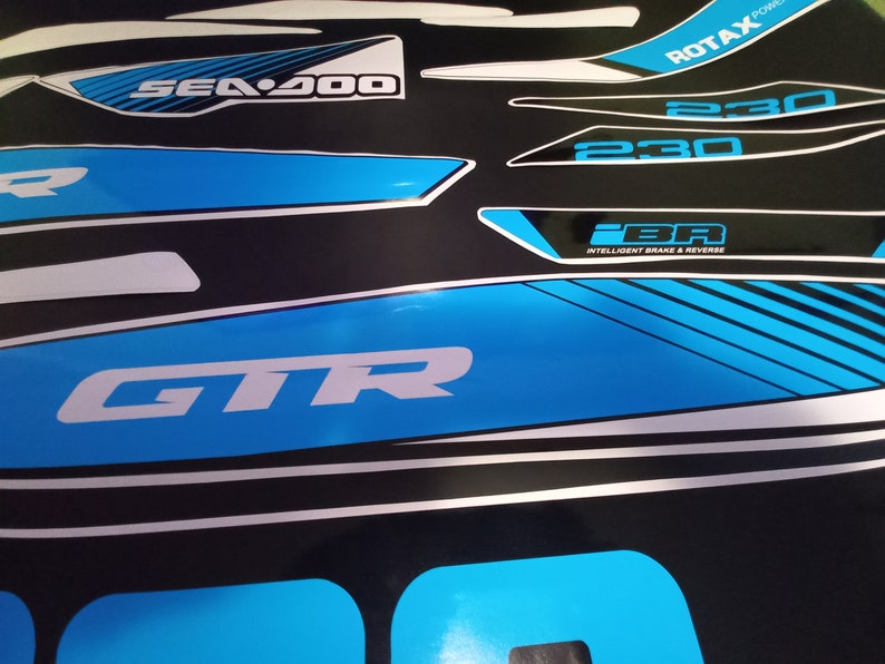 May include: A set of blue and white decals for a Sea-Doo GTR watercraft. The decals feature the Sea-Doo logo, the model name GTR, and the engine size 230. The decals also include the text "iBR" for Intelligent Brake & Reverse and "ROTAX Power".