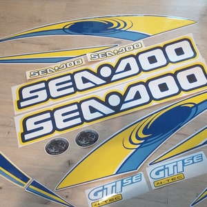 May include: A set of yellow and blue Sea-Doo watercraft decals. The decals feature the Sea-Doo logo and the text "Sea-Doo" and "GTISe 4-TEC".
