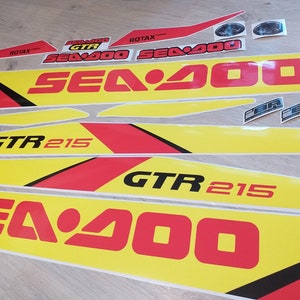 May include: A set of yellow and red Sea-Doo decals with black lettering. The decals include the words "Sea-Doo", "GTR 215", and "Rotax".