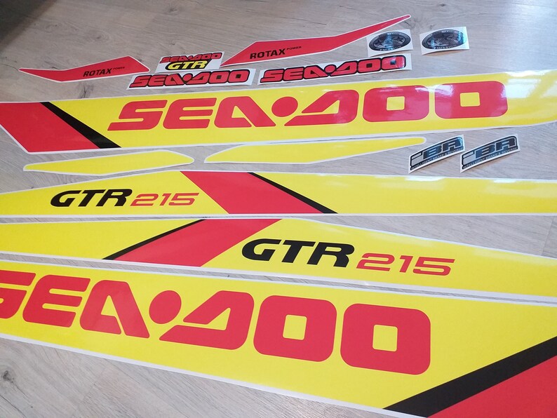 May include: A set of yellow and red Sea-Doo decals with black lettering. The decals include the words "Sea-Doo", "GTR 215", and "Rotax".