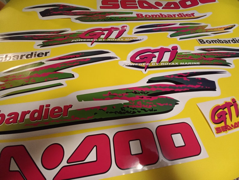 May include: A set of Sea-Doo GTI decals in pink, green, and black. The decals feature the Sea-Doo logo, the words "GTI" and "Powered by Rotax Marine", and the word "Bombardier".