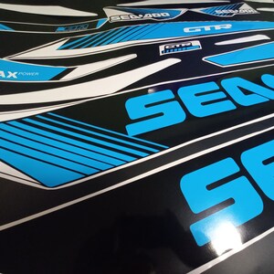 May include: A set of blue and white decals for a Sea-Doo watercraft. The decals feature the Sea-Doo logo, the words "Sea-Doo", "GTX", and "ROTAX POWER".