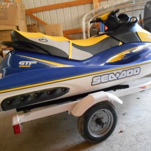 May include: A blue and white Sea-Doo GTI SE watercraft with yellow accents. The jet ski is on a trailer with a single wheel.