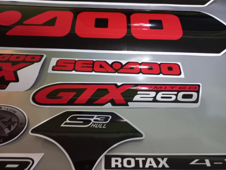 May include: A close-up of various Sea-Doo decals, including a black and red "Sea-Doo GTX 260 Limited" sticker, a black and white "S3 Hull" sticker, and a black and white "ROTAX 4-TEC" sticker.