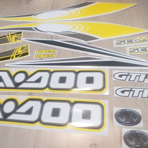 May include: A set of black, white, and yellow decals for a Sea-Doo GTI SE 2000 jet ski. The decals include the words "Sea-Doo", "GTI SE", "4-TEC", and "Emission".