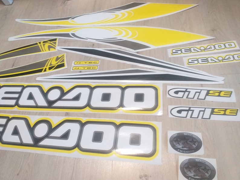 May include: A set of black, white, and yellow decals for a Sea-Doo GTI SE 2000 jet ski. The decals include the words "Sea-Doo", "GTI SE", "4-TEC", and "Emission".
