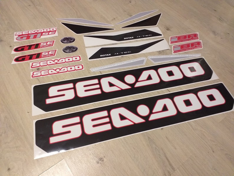 May include: A set of black and white Sea-Doo decals with red accents. The decals include the Sea-Doo logo, the words "Sea-Doo", "GTISE", and "ROTAX 4-TEC".