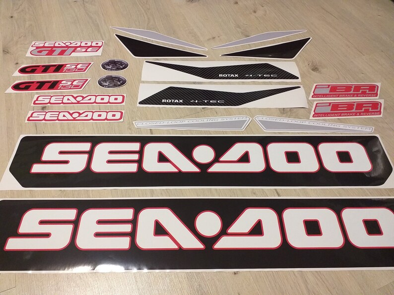 May include: A set of black and white decals with red accents for a Sea-Doo watercraft. The decals include the words "Sea-Doo", "GTISE", "ROTAX", and "Intelligent Brake & Reverse".