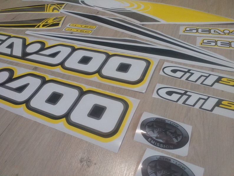May include: A set of black and white decals with yellow trim. The decals feature the text "Sea-Doo", "GTIS", and "200".