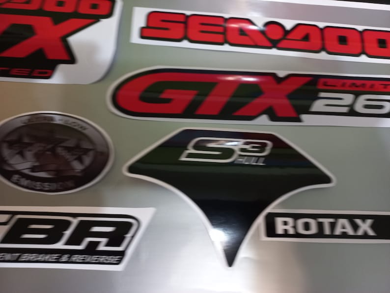 May include: A collection of stickers featuring various logos and designs. The stickers are black, white, red, and gray. The logos include "Sea-Doo", "GTX", "Limit 260", "S3 Hull", "BR", and "Rotax".