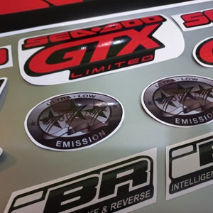 May include: A set of black and red decals with the text "Sea-Doo GTX Limited" and "Ultra Low Emission" in white. The decals are designed for a motorcycle or watercraft.