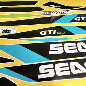 以下が含まれることがあります： 青色のアクセントが付いた黒と白のシー-ドゥーのデカールセット。デカールには、シー-ドゥーのロゴ、"シー-ドゥー"、"GTI"、"130"のテキスト、そして"ロタックスパワー"の文字が書かれています。