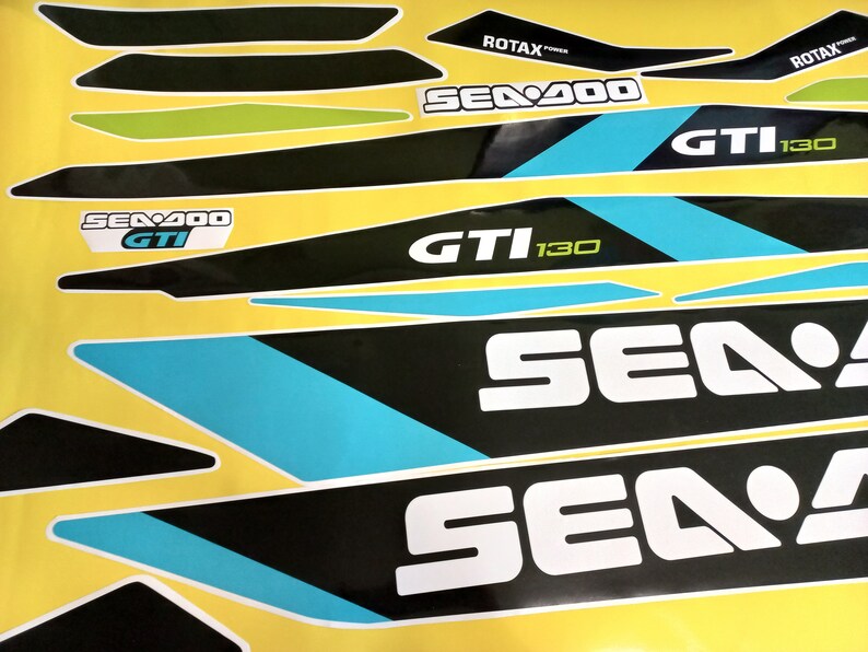 以下が含まれることがあります： 青色のアクセントが付いた黒と白のシー-ドゥーのデカールセット。デカールには、シー-ドゥーのロゴ、"シー-ドゥー"、"GTI"、"130"のテキスト、そして"ロタックスパワー"の文字が書かれています。